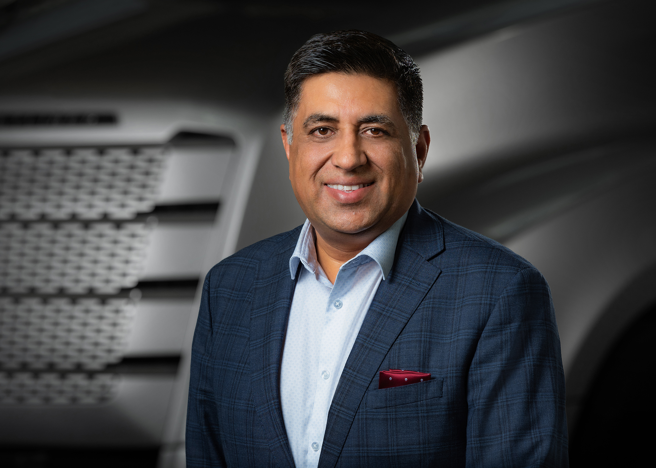 Professional headshot of a man in navy blazer and light blue shirt smiling at camera