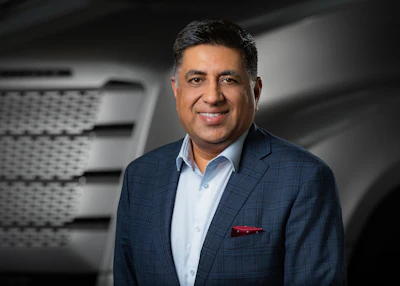 Professional headshot of a man in navy blazer and light blue shirt smiling at camera