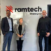 Three business professionals standing in front of Ramtech Orama group office wall signage