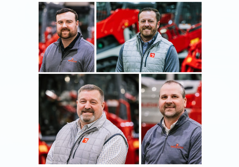 Four men in professional outdoor attire smiling at camera with red farm equipment in background