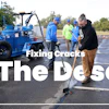 Asphalt repair crew filling cracks in desert parking lot with blue equipment and workers