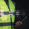 Construction worker in safety vest using tablet with digital checklist interface overlay