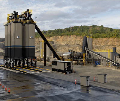 Industrial concrete batch plant with tall storage silos and conveyor systems at an active quarry site