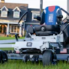 White and black zero-turn radius mower with blue USA branding on residential lawn