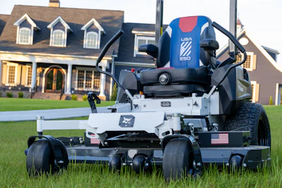 White and black zero-turn radius mower with blue USA branding on residential lawn