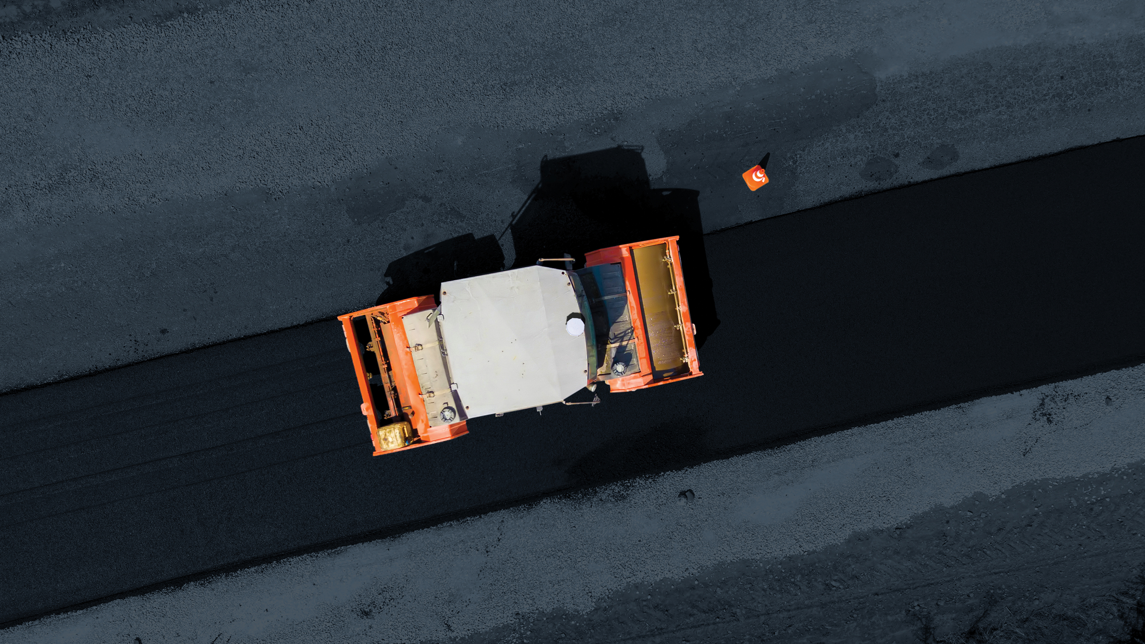 Aerial view of orange and white truck on black asphalt road