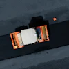Aerial view of orange and white truck on black asphalt road