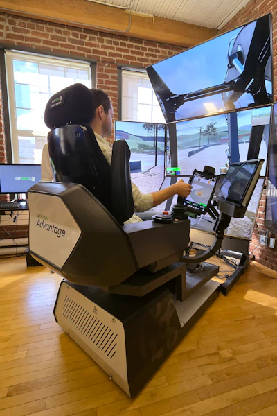 Person using racing simulator with multiple monitors in brick-walled indoor space