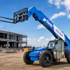 Blue Genie telehandler with extended boom on construction site next to unfinished concrete building