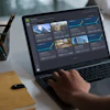 Designer working on laptop displaying portfolio gallery with architectural images in modern workspace