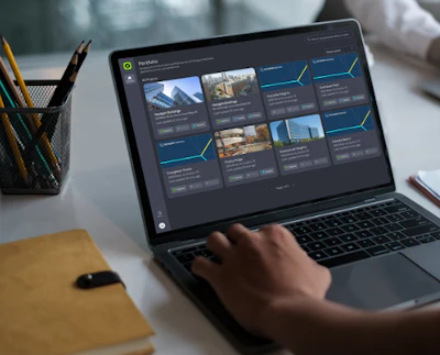 Designer working on laptop displaying portfolio gallery with architectural images in modern workspace