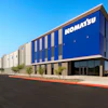 Modern Komatsu industrial facility with blue and white striped facade under clear blue sky