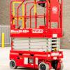 Red and yellow MEC Micro26-XD+ scissor lift platform with safety cage and hydraulic base on concrete floor