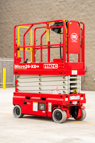 Red and yellow MEC Micro26-XD+ scissor lift platform with safety cage and hydraulic base on concrete floor