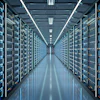 Modern data center with rows of server racks illuminated by blue and yellow indicator lights under fluorescent ceiling panels