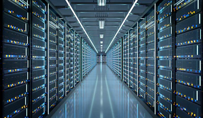 Modern data center with rows of server racks illuminated by blue and yellow indicator lights under fluorescent ceiling panels