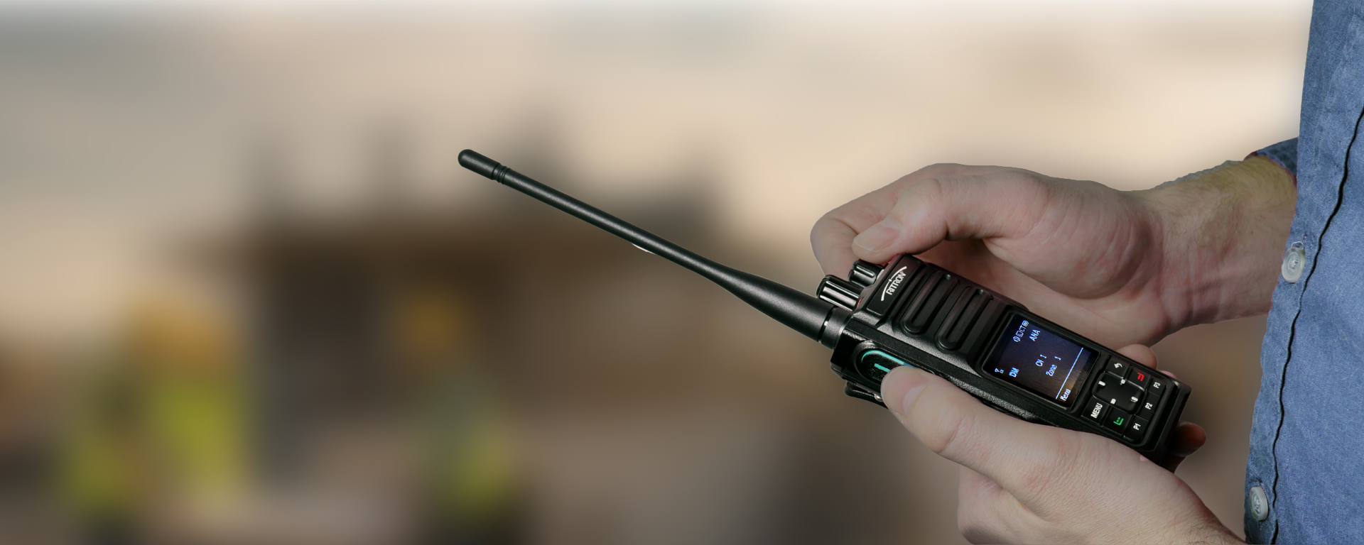 Person holding a black two-way radio with antenna outdoors