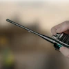 Person holding a black two-way radio with antenna outdoors