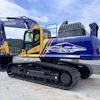 Blue and yellow Komatsu excavator next to Ohio Steel branded trailer at outdoor equipment display