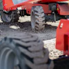 Red agricultural equipment with large tires parked on sandy ground