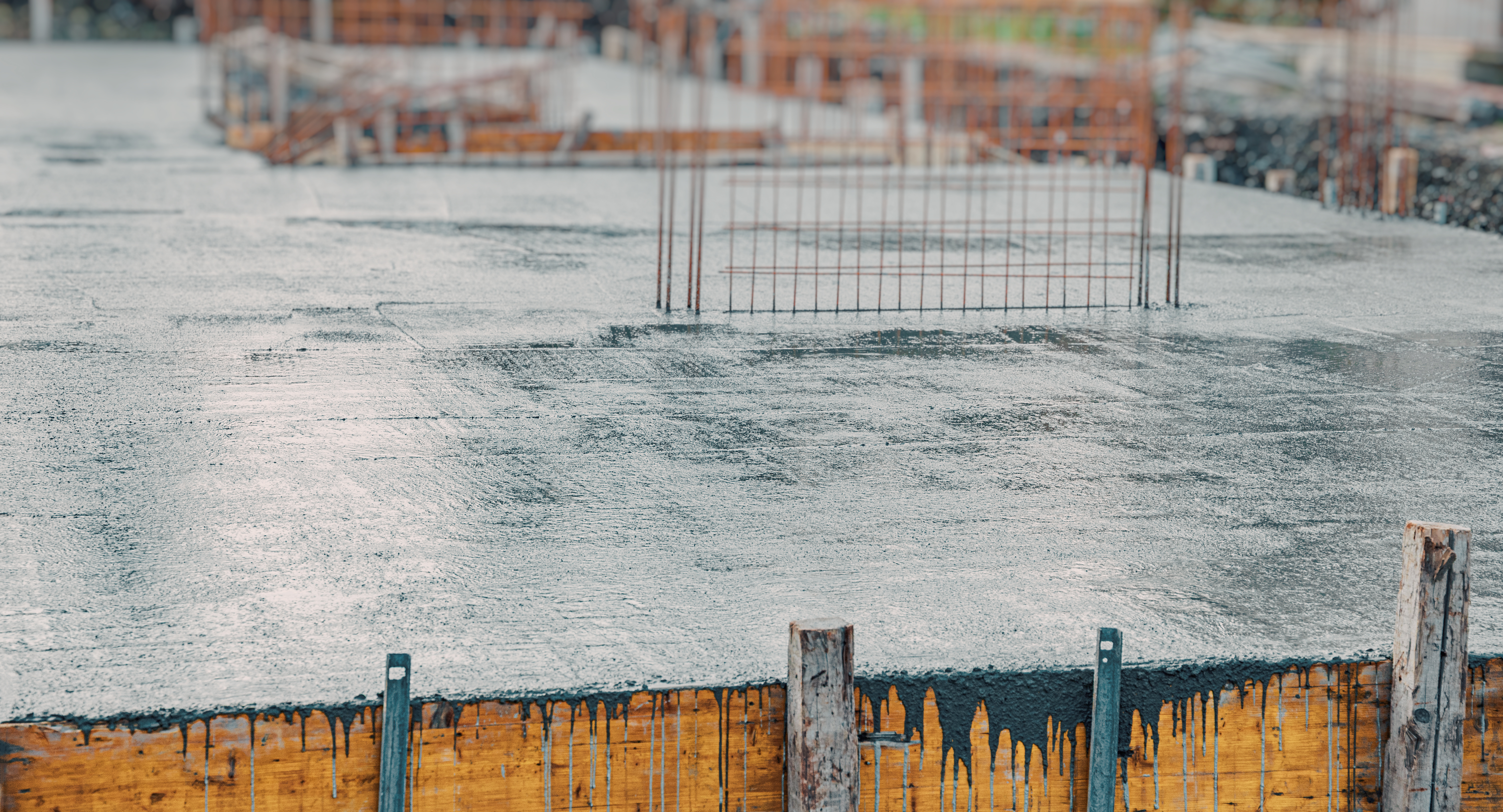 Wet concrete foundation with temporary metal fencing at active construction site