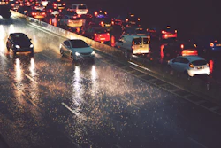 Heavy traffic on wet highway at night with vehicle headlights and taillights reflecting on rain-soaked pavement