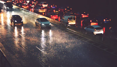 Heavy traffic on wet highway at night with vehicle headlights and taillights reflecting on rain-soaked pavement