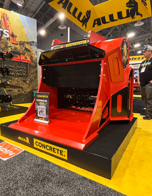 Red concrete mixer truck on display at industrial equipment exhibition with yellow Allu branding