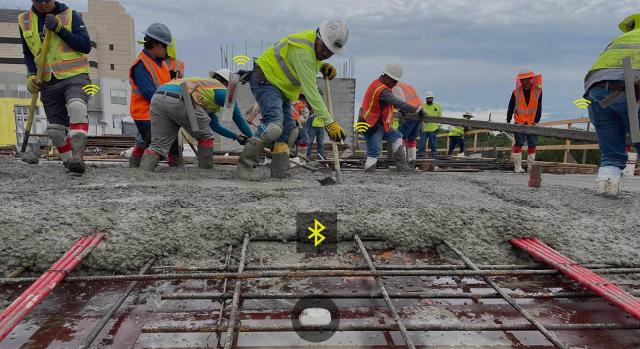 Construction workers in safety gear pouring concrete on a building site with yellow marking visible