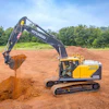 Yellow and black Hyundai excavator digging red soil at a construction site with trees in background