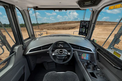 Interior cockpit view of autonomous vehicle with digital displays overlooking barren landscape