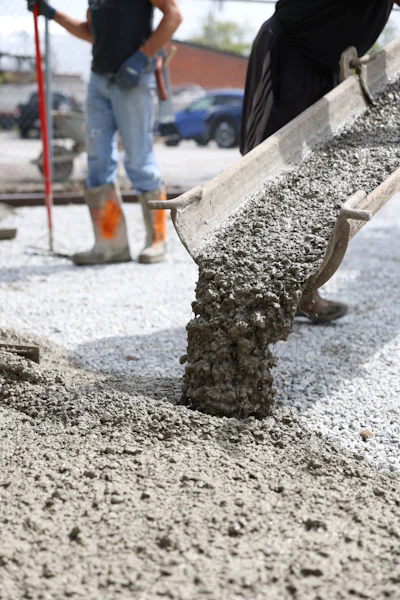 Construction workers pouring and spreading concrete with shovels at a job site