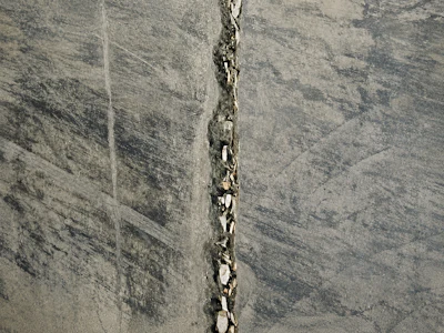 Vertical crack running through gray concrete surface with weathered texture