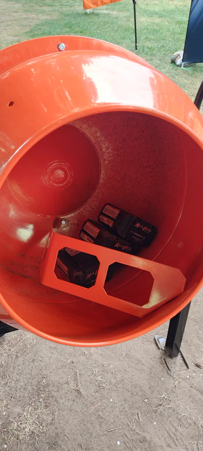 Red spherical container with black battery compartment displayed outdoors on grass