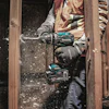 Construction worker using Makita cordless drill on wooden door frame with sawdust flying