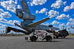 Decommissioned aircraft tail suspended above white ground support tug vehicle in desert aviation facility