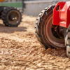 Red construction compactor wheel on sandy work site with heavy machinery in background