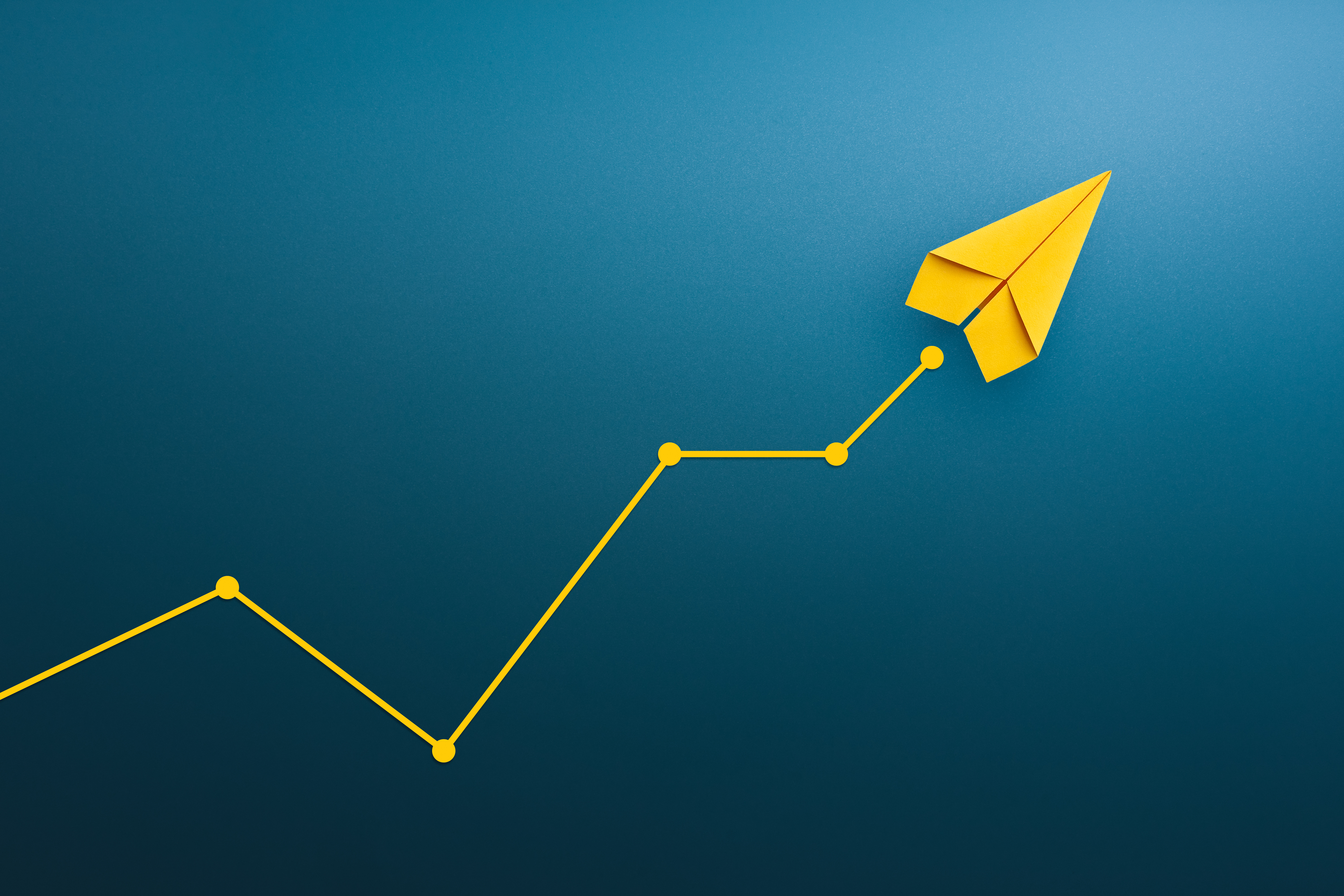 Yellow paper airplane ascending along an upward trending line graph on blue background