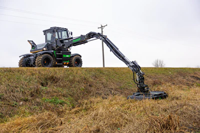 Black and green telescopic handler with extended boom operating in harvested field near power lines