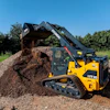 Hyundai HT30 compact track loader dumping gravel at a construction site with trees in background