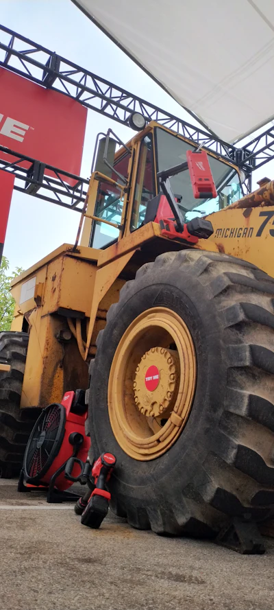 Yellow Michigan wheel loader with large tire displayed at outdoor equipment exhibition with red signage