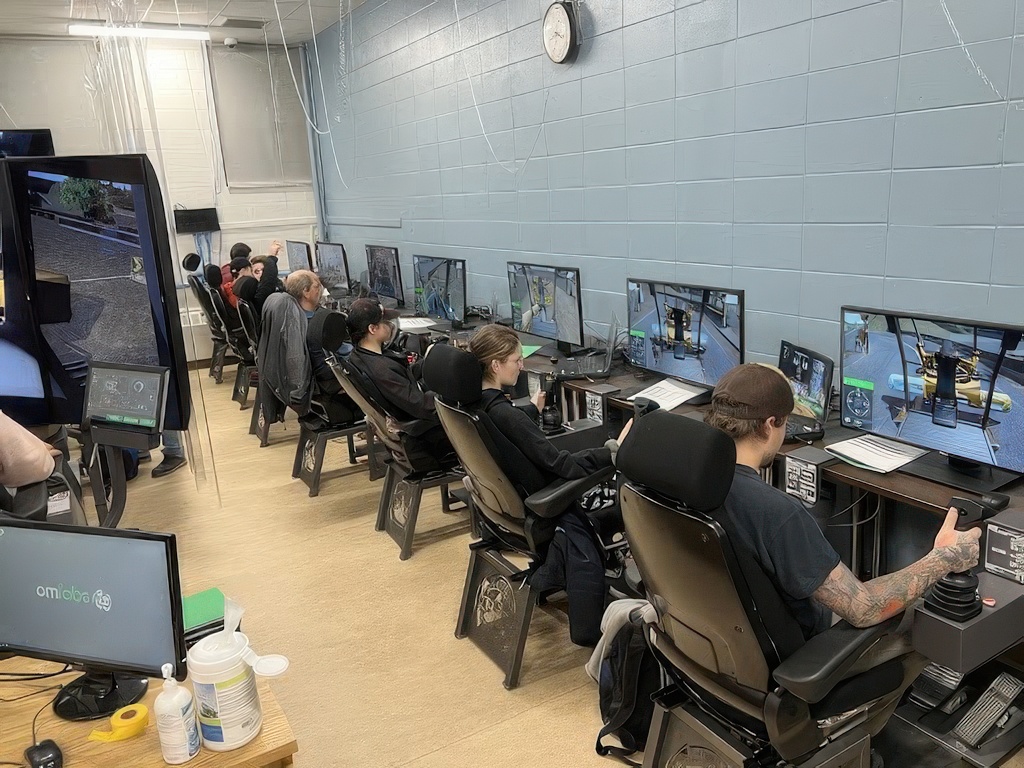Gaming facility with multiple players seated at computer workstations in a light-filled room with blue-tiled walls