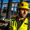 Construction worker wearing yellow KASK safety helmet and neon green reflective vest at industrial building site