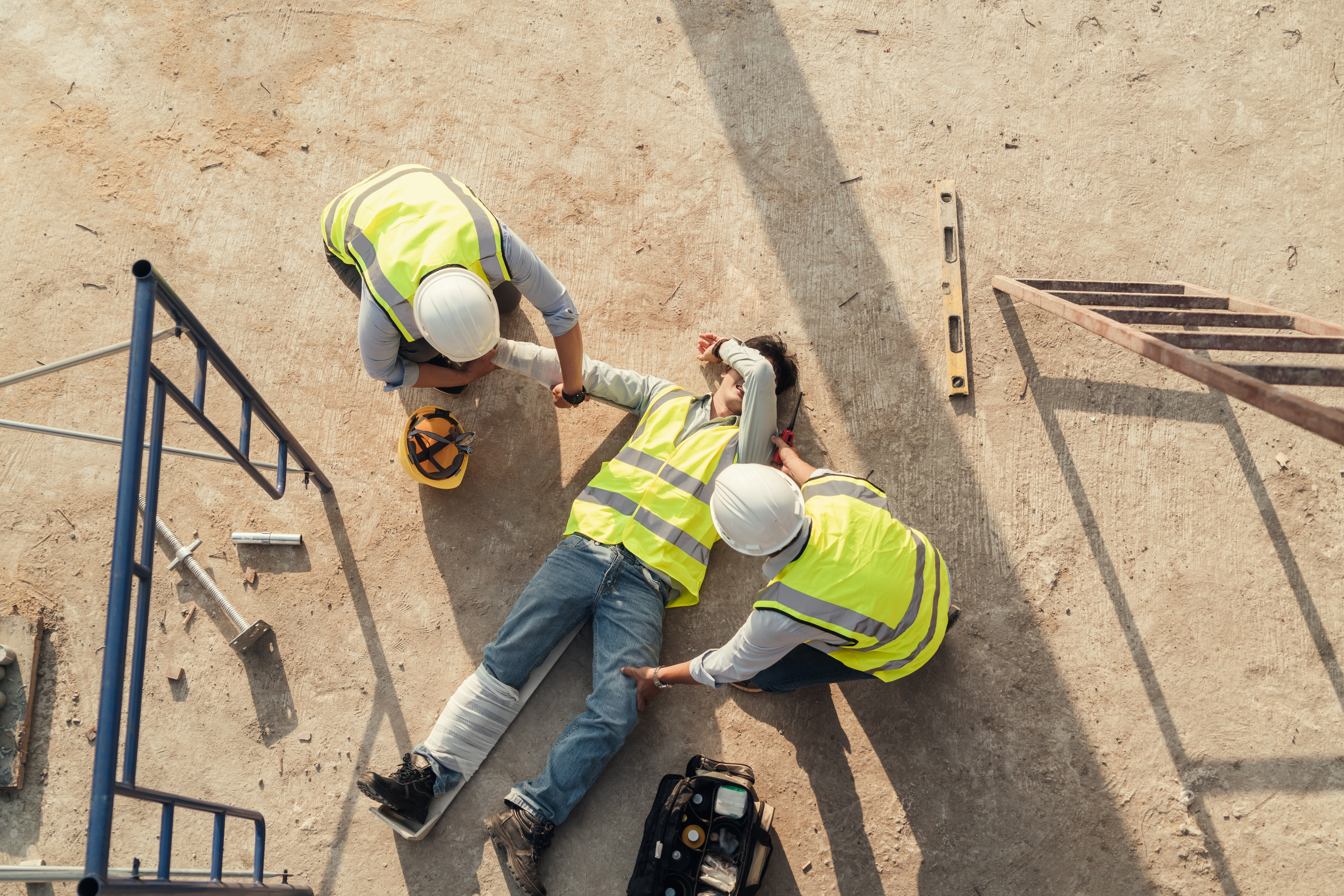 Two construction workers in safety vests and hard hats reviewing plans at a job site