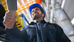 Construction worker in blue hard hat looking upward on industrial job site
