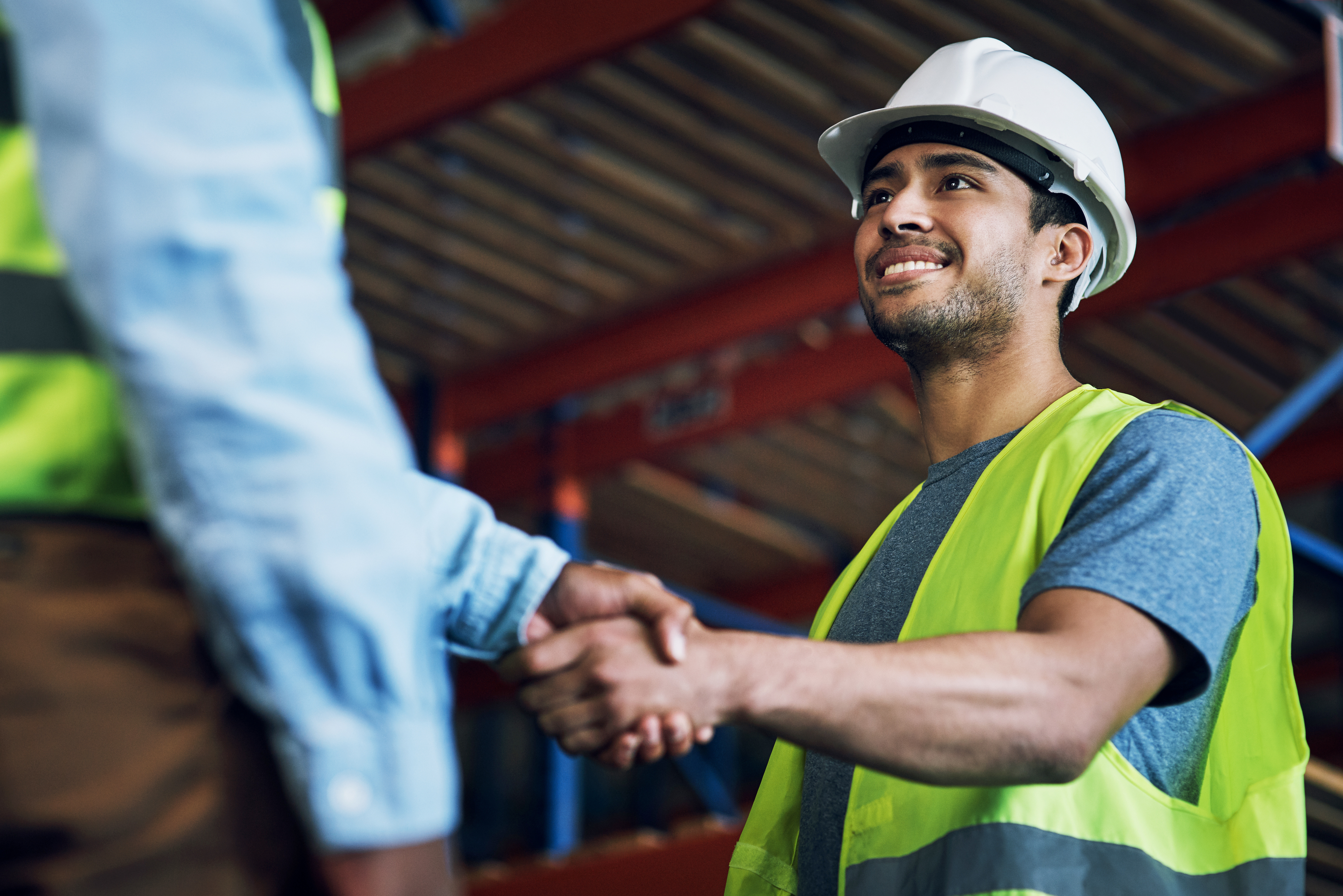 Construction workers in safety gear shaking hands at a warehouse site