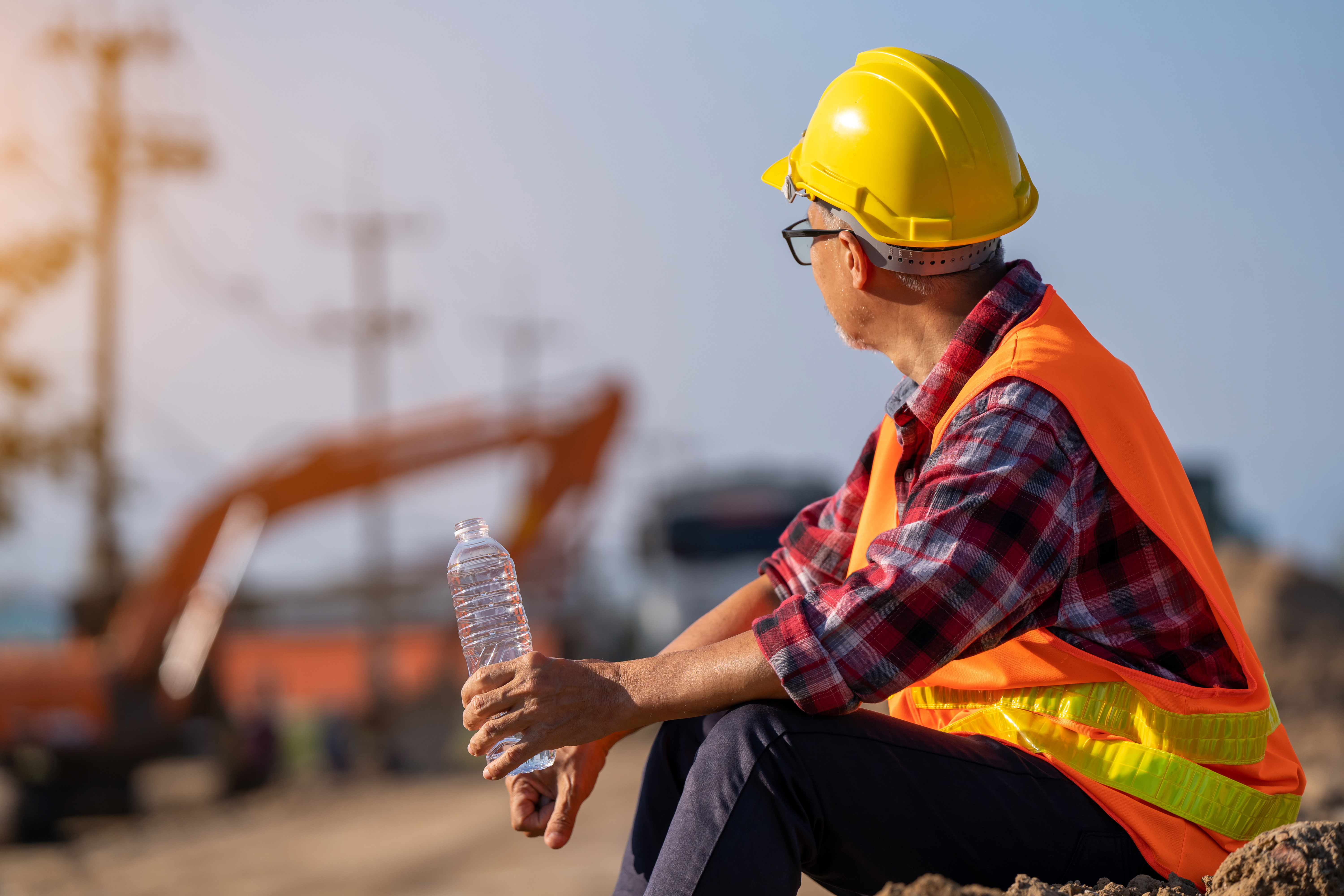 Construction worker in safety gear holding water bottle at job site