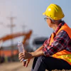 Construction worker in safety gear holding water bottle at job site