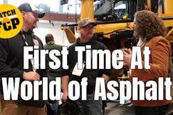 People discussing at World of Asphalt event near yellow construction equipment