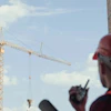 Construction worker in red safety gear operating tower crane at building site